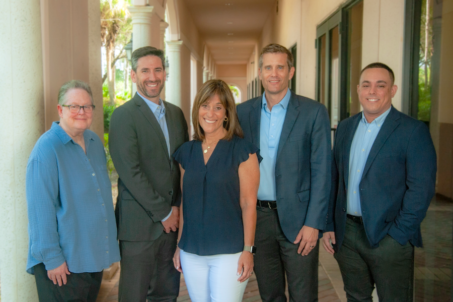 Group portrait of the Core Wealth Management team standing together in a sunlit outdoor corridor.