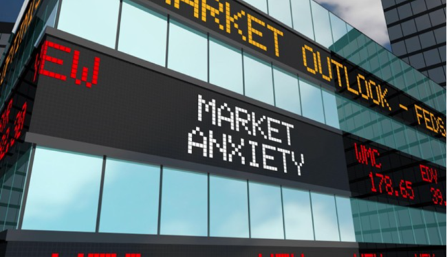 A digital stock ticker display on a building showing 'Market Anxiety' and 'Market Outlook' in a city setting