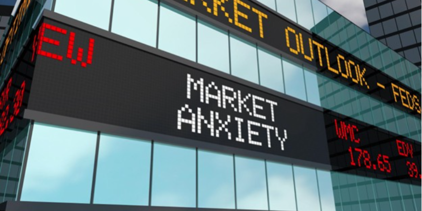 A digital stock ticker display on a building showing 'Market Anxiety' and 'Market Outlook' in a city setting